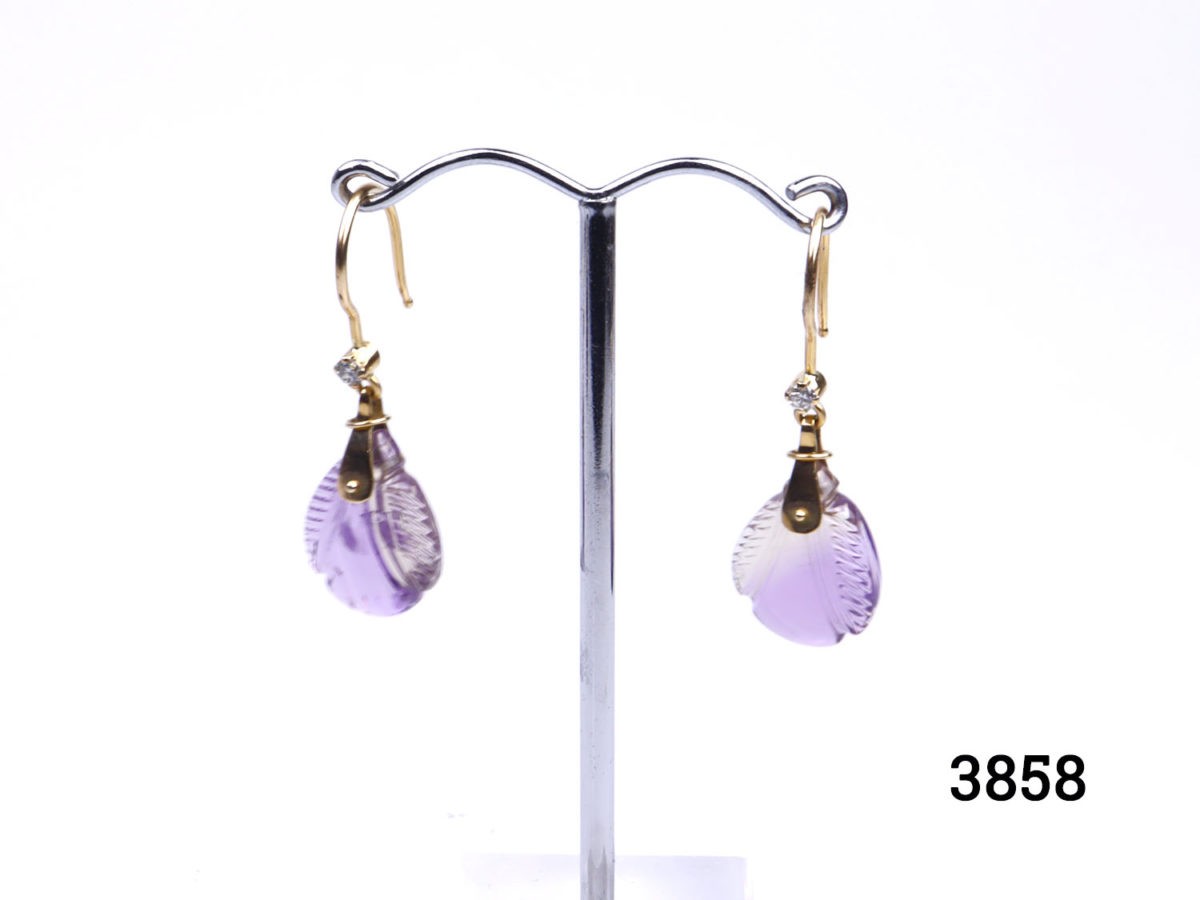 Unique 18 karat gold dangle earrings set with carved amethystine and small diamond. Hallmarked 18k for 18 karat gold. Drop length 40mm. Amethystine is a hybrid of amethyst and citrine. Stone measures 12mm at widest point. Main photo with both earrings shown on display stand