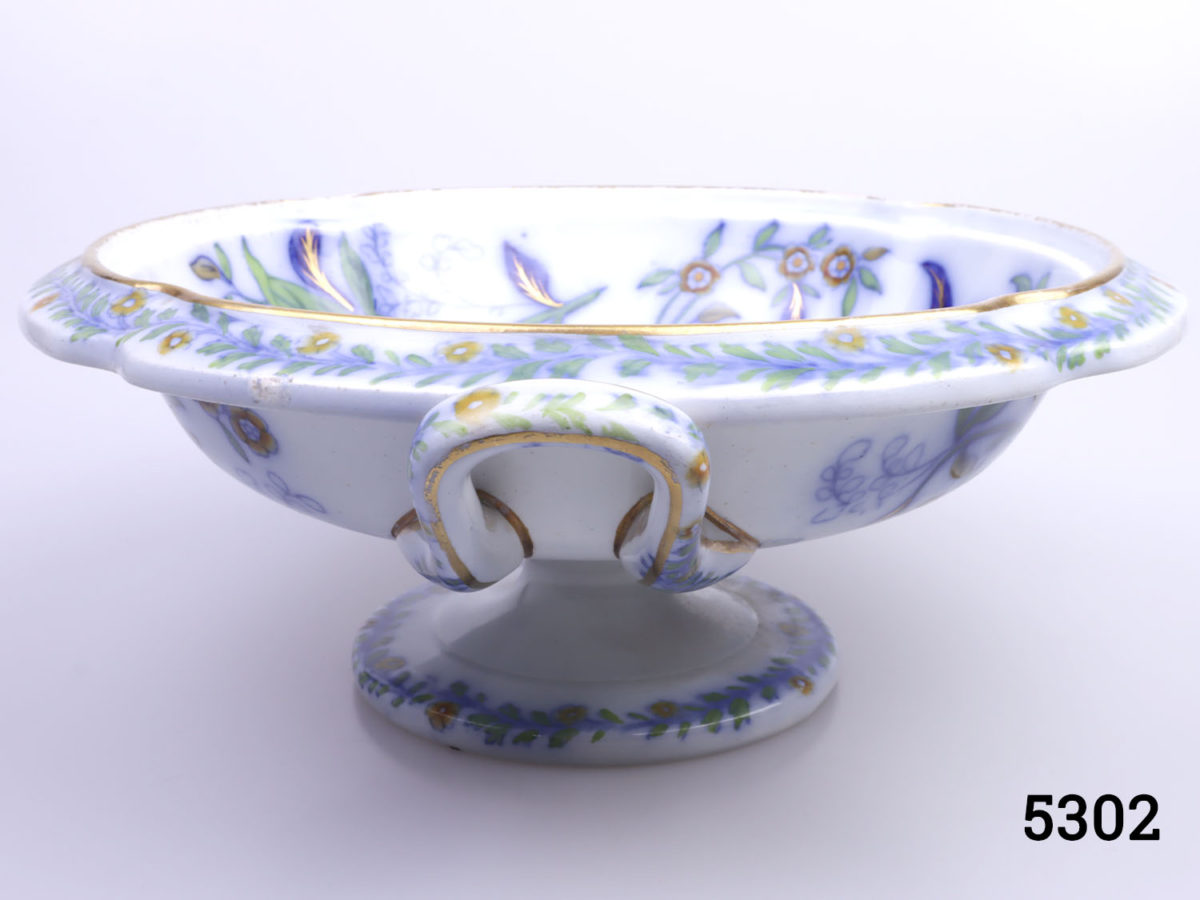 Antique Copeland & Garrett pedestal bowl with handles. Hand decorated with floral scene of blue, orange and gilt. Stamped with makers mark to the base. c1833-1847 Measures 95mm in diameter at base and 215mm across the top Photo of bowl from an eye level angle with one handle in centre foreground