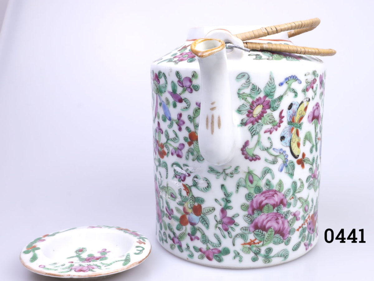 Antique Famille Rose teapot. Hand-decorated in a floral scene with birds and butterflies. (The spout tip has had a professional repair). Measures 130mm in diameter at base and 210mm tall with handle extended. Photo of teapot with lid removed and to the left side seen with spout in the foreground