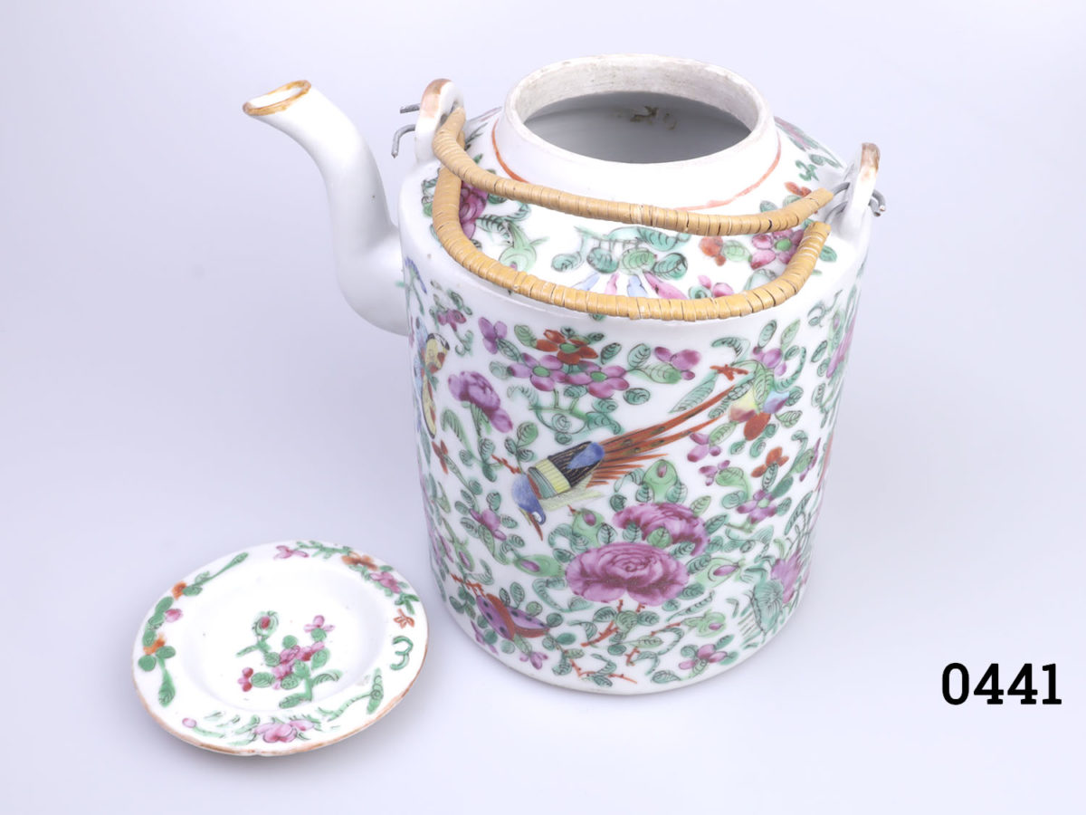 Antique Famille Rose teapot. Hand-decorated in a floral scene with birds and butterflies. (The spout tip has had a professional repair). Measures 130mm in diameter at base and 210mm tall with handle extended. Photo of teapot with lid removed and seen from a slight raised angle partially showing interior