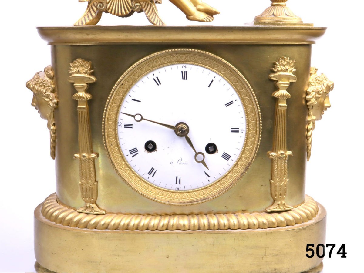 Antique French clock c1810s. Heavy clock in gilt ormolu from the first French empire. Fine detail decoration with an angel reading by firelight. Back cover missing. Key included. Fully serviced and guaranteed for 1 year. Close up of clock face seen from full on front view