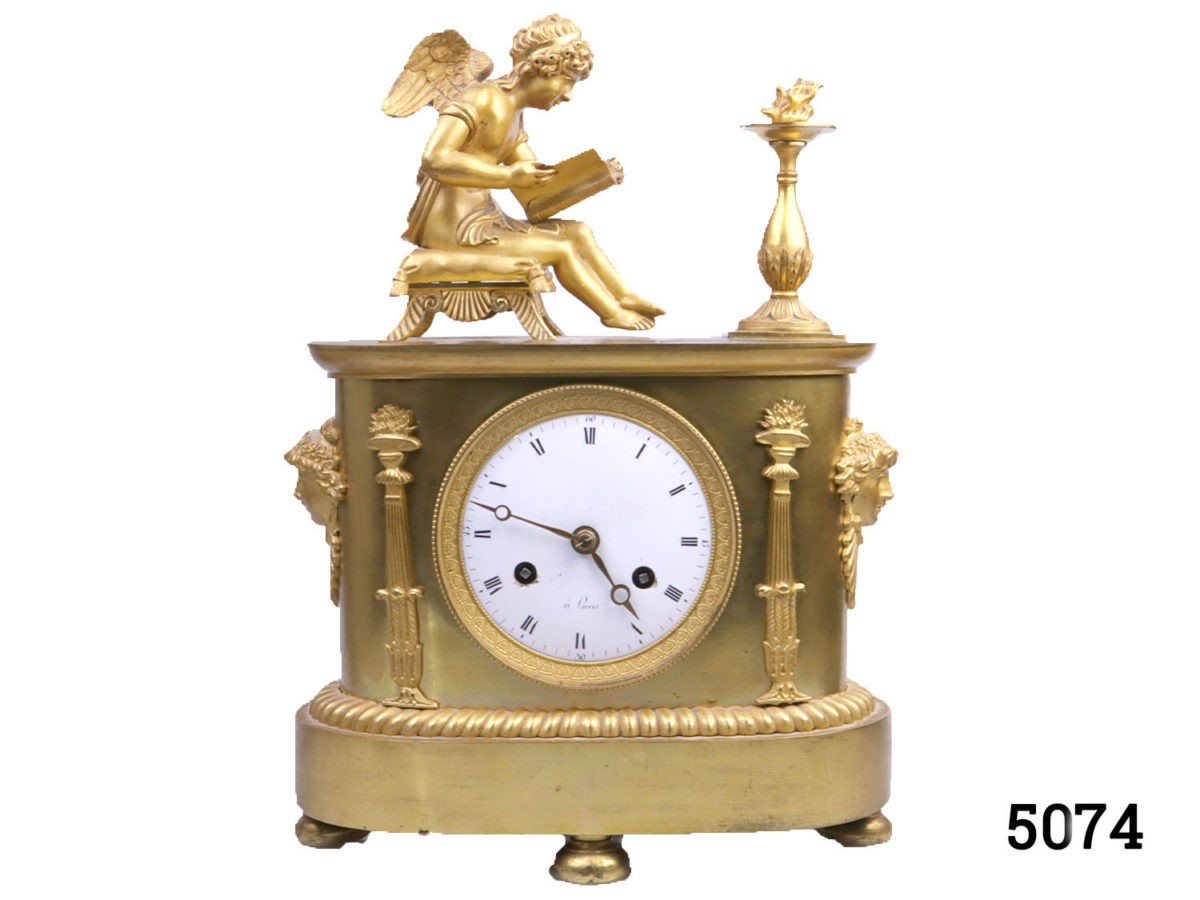 Antique French clock c1810s. Heavy clock in gilt ormolu from the first French empire. Fine detail decoration with an angel reading by firelight. Back cover missing. Key included. Fully serviced and guaranteed for 1 year. Main photo looking at the clock from the front