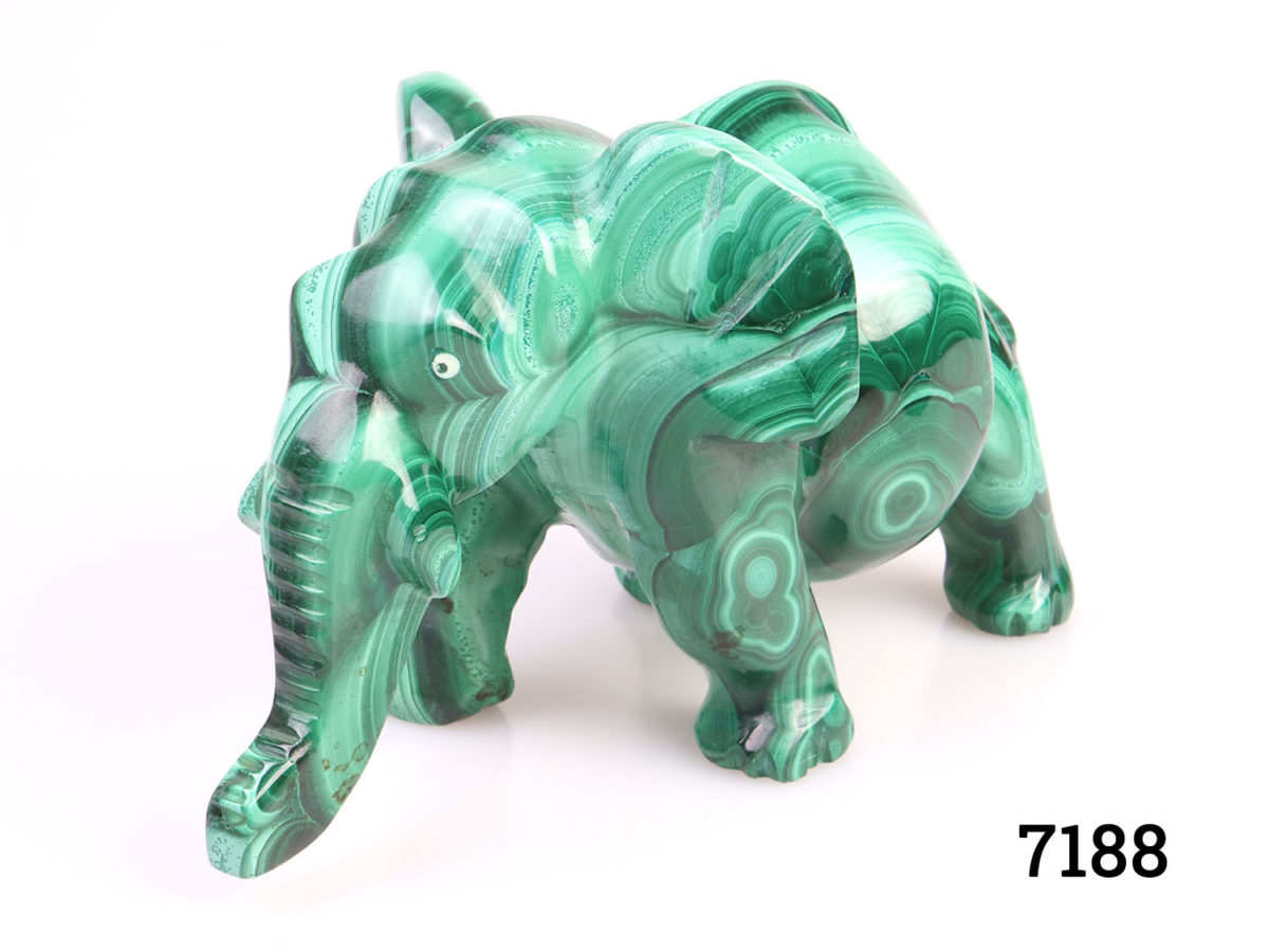 Heavy elephant ornament carved out of one piece of malachite. Smooth finish with no rough edges. Main photo showing elephant from an eye level with trunk to bottom left