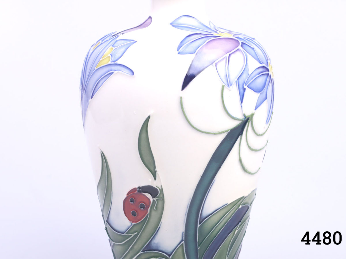 Signed Moorcroft vase by Rachel Bishop called "Fly Away Home". Decorated with blue flowers and ladybirds. No original box. Measures 40mm in diameter at base and 35mm in diameter across the top. Close up photo of the decoration on one side of the vase