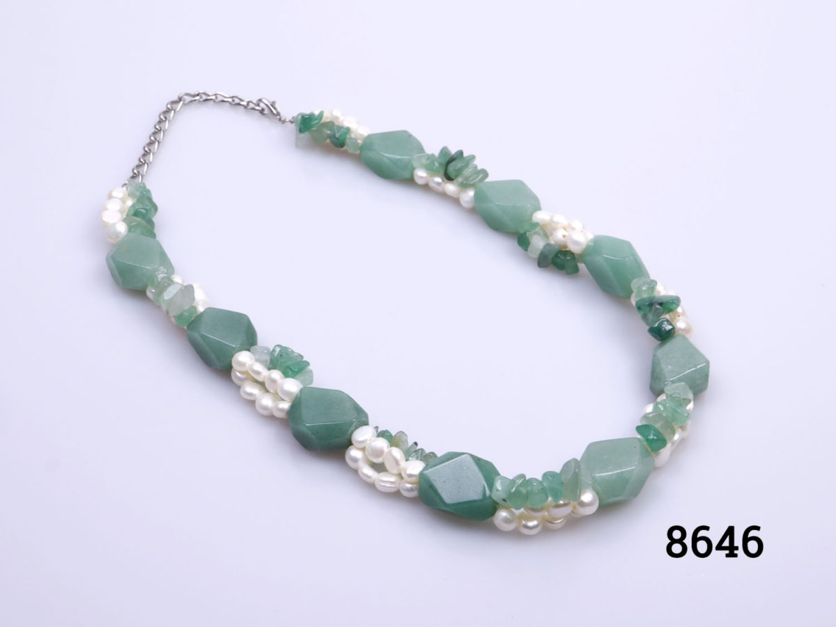 Vintage chunky pearl and aventurine necklace. Large pieces of aventurine separated by 3 short strands;2 of freshwater pearls and 1 of small aventurine pieces. Silver colour metal clasp and chain. Slightly extendable from 420mm to 500mm Photo of necklace on a flat surface laid diagonally with clasp end at top left corner