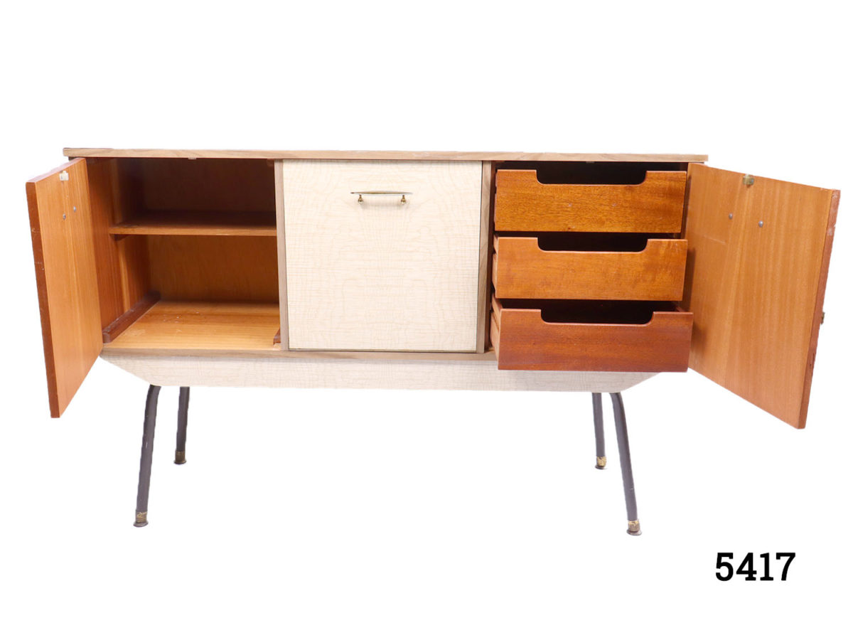 1970s Retro melamine sideboard with 3 compartments; cupboard to left with shelf, drop down central compartment and door concealing 3 drawers to the right. Measurement at base (legs) 1105mm by 355mm Photo of left and right side doors open