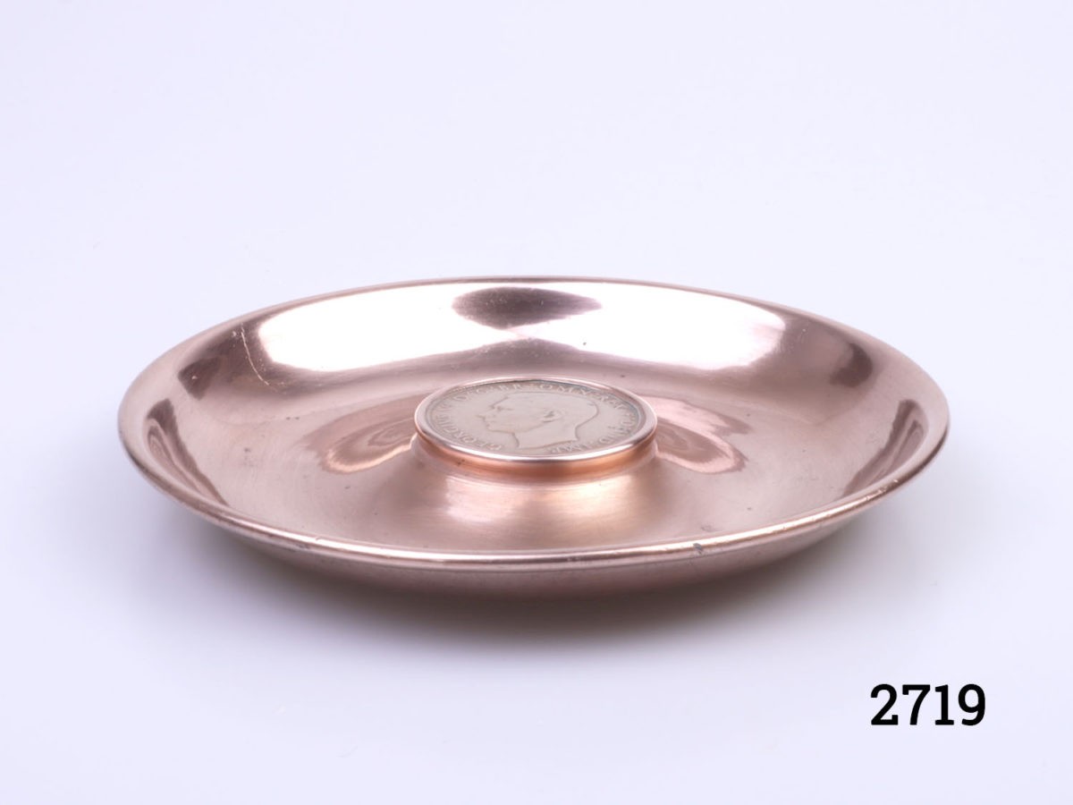 Small circular copper pin/coin tray with a 1937 copper one old pence to the centre. Measures 108mm in diameter. Main photo of tray from an eye level angle showing depth