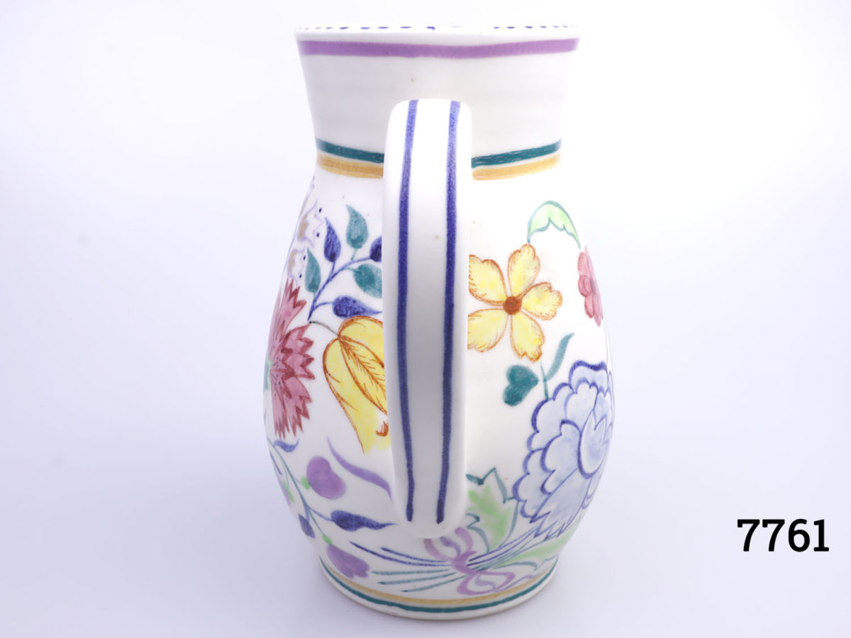 Vintage medium sized Poole Pottery jug. Hand decorated with multi-coloured flowers on a cream background with cream interior. Measures 85mm in diameter at base Photo of handle end of jug with handle central in the photo
