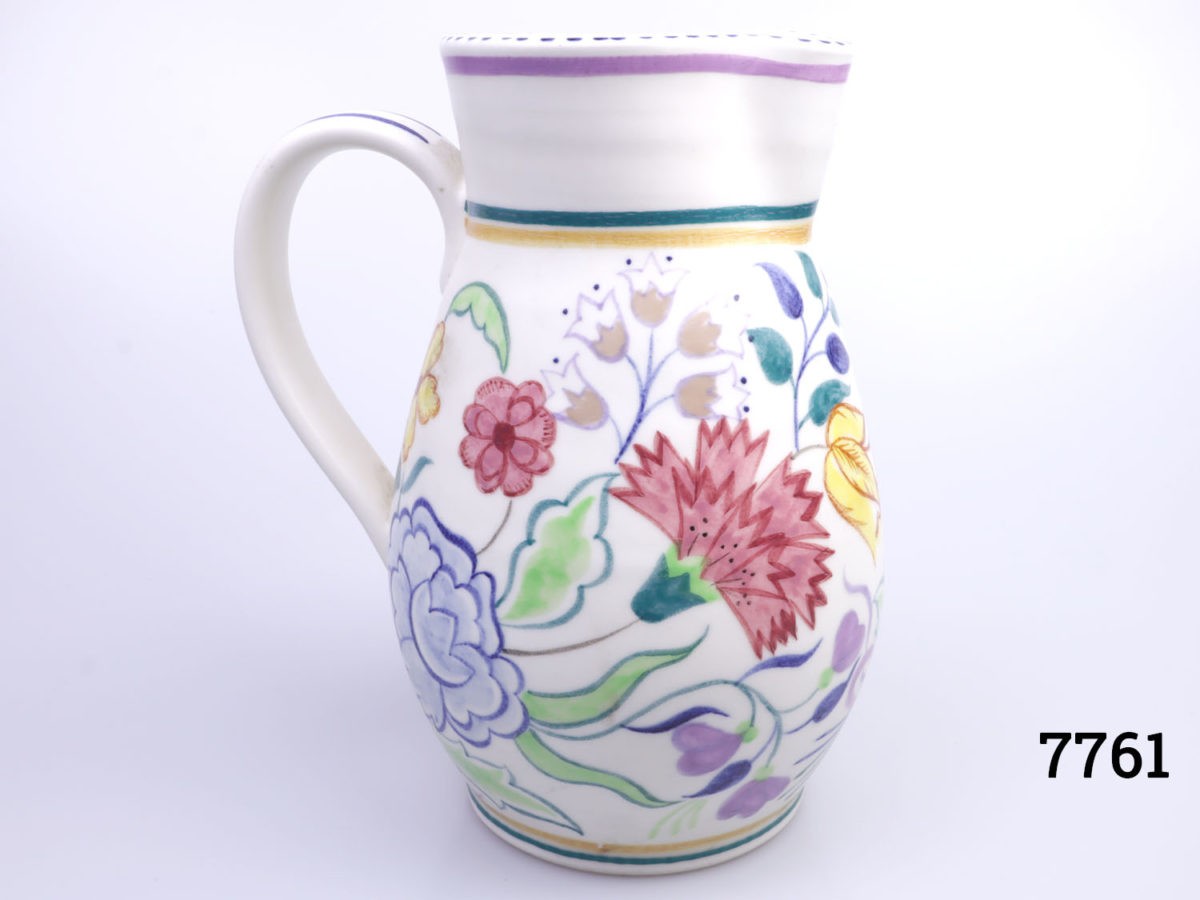Vintage medium sized Poole Pottery jug. Hand decorated with multi-coloured flowers on a cream background with cream interior. Measures 85mm in diameter at base Main photo showing jug from an eye level side angle with handle to the left of picture