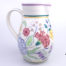 Vintage medium sized Poole Pottery jug. Hand decorated with multi-coloured flowers on a cream background with cream interior. Measures 85mm in diameter at base Main photo showing jug from an eye level side angle with handle to the left of picture