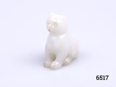 Vintage Oriental white jade cat ornament. Carved from one piece of jade and in a seated pose. Main photo of cat at a diagonal angle with head facing left