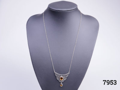 Vintage silver necklace with attached pendant. Pendant adorned with an oval cut orange stone to the centre and smaller orange stone hanging beneath. Pendant drop length 30mm Main photo showing necklace displayed on a stand seen looking straight on
