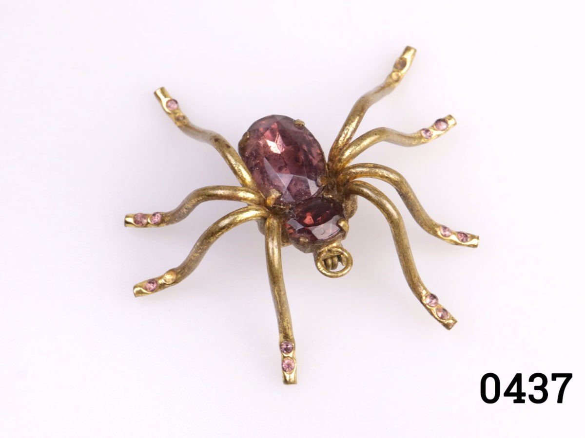 Vintage Slovakian brass spider brooch with amethyst glass body. Some smaller glass pieces on legs missing. Can also be worn as a pendant. Photo of spider from above with front end in the foreground