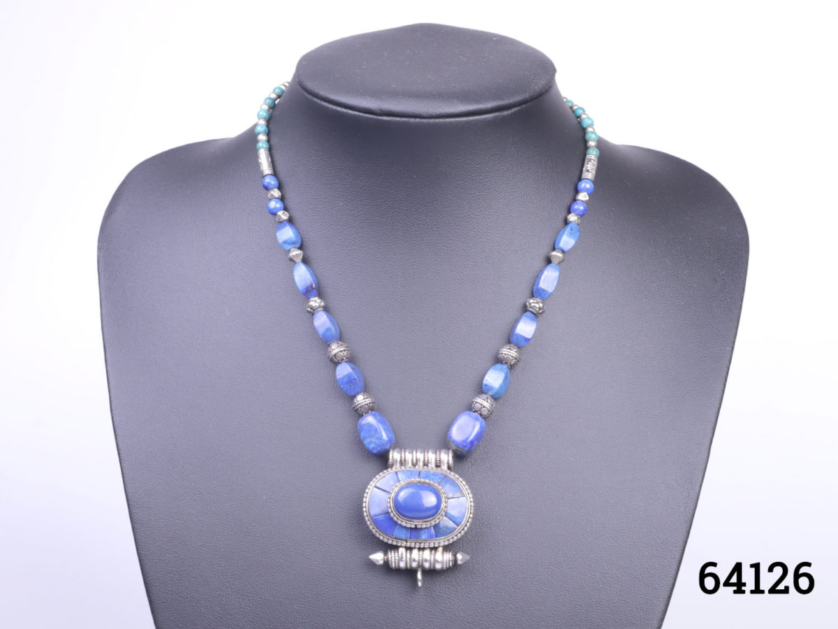 Vintage Tibetan silver necklace with turquoise and lapis lazuli beads and a lapis lazuli box pendant. Pendant has a secret compartment that opens at the back and measures 38mm long by 30mm wide Main photo of necklace displayed on a stand seen from the front