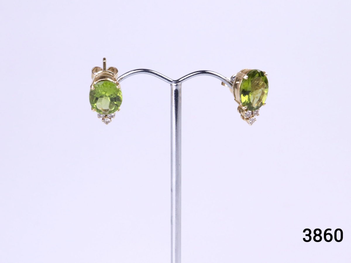 Modern and unique pair of 18 karat gold stud earrings set with oval cut peridot and 3 small diamonds to each. Peridot stone measure 13mm by 8mm. Earrings weight 5.2grammes. Box included Main photo of both earrings displayed on a stand