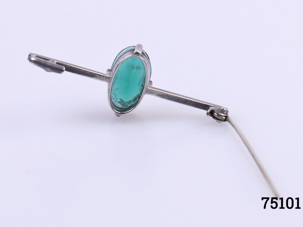Art Deco sterling silver bar brooch with emerald green coloured glass stone to centre. Hallmarked silver and signed RK to the back. Stone measures 15mm by 8mm. Photo of back of brooch with pin open showing silver hallmark