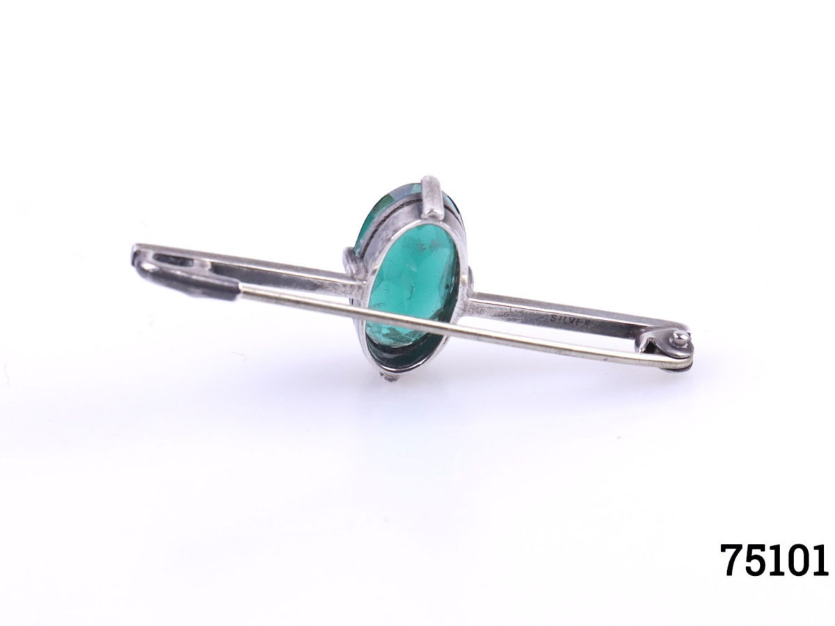 Art Deco sterling silver bar brooch with emerald green coloured glass stone to centre. Hallmarked silver and signed RK to the back. Stone measures 15mm by 8mm. Photo of back of brooch with pin closed