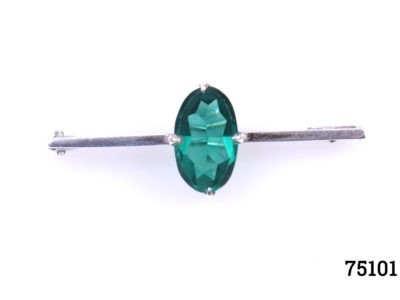 Art Deco sterling silver bar brooch with emerald green coloured glass stone to centre. Hallmarked silver and signed RK to the back. Stone measures 15mm by 8mm. Main photo showing brooch from a front view angle