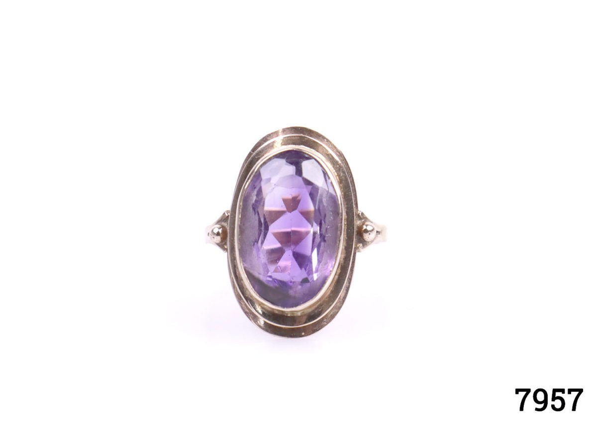 Rose gold dress ring with oval cut amethyst. Worn hallmark on outer band of ring at back. Ring front measures 23mm by 12mm. Ring size Q / 8. Photo of ring on a flat surface seen from the front