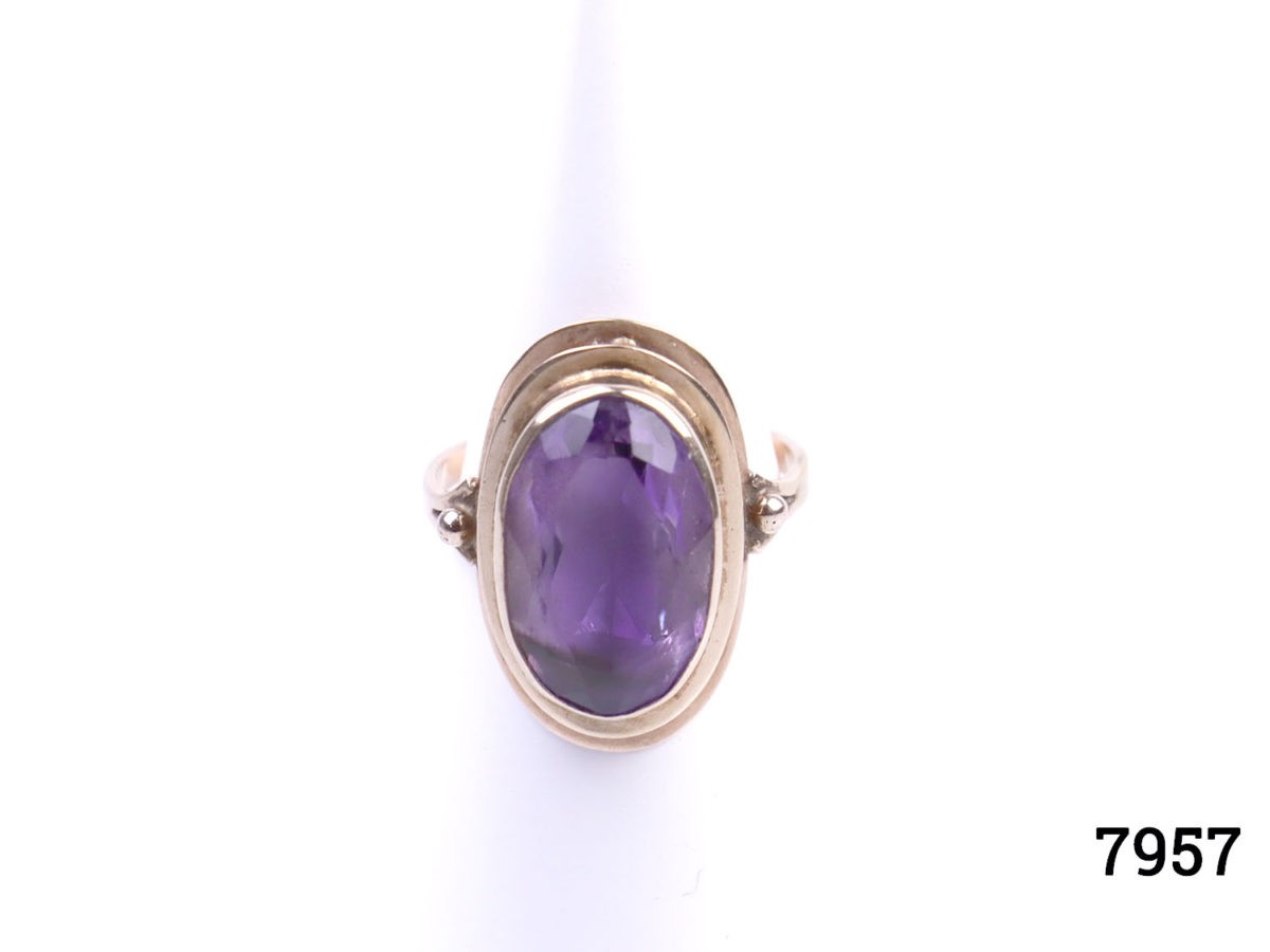 Rose gold dress ring with oval cut amethyst. Worn hallmark on outer band of ring at back. Ring front measures 23mm by 12mm. Ring size Q / 8. Main photo of ring on display stand seen from the front