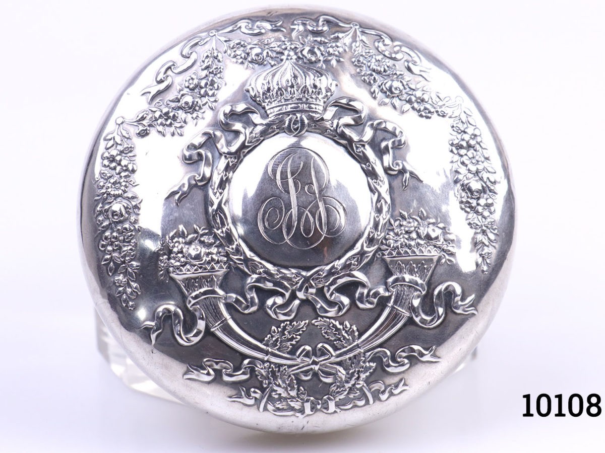 Sterling silver lidded glass pot. Vintage pot with heavily embossed silver lid Measures 85mm in diameter. Close up photo of the top of lid showing the intricate embossed work and stylised initials JB to the centre