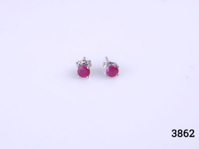 Modern sterling silver stud earrings set with round cut cloudy ruby stones to each. Hallmarked 925 for sterling silver. Earrings weight 1.4 grams. Box included. Main photo showing both earrings on a flat surface seen from the front