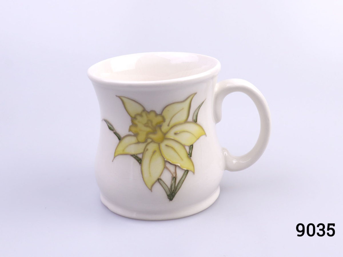Vintage Moorcroft mug in daffodil pattern. Impressed Moorcroft mark to the base. c1980s. Measures 80mm in diameter at base Main photo of mug from an eye level with handle to the right