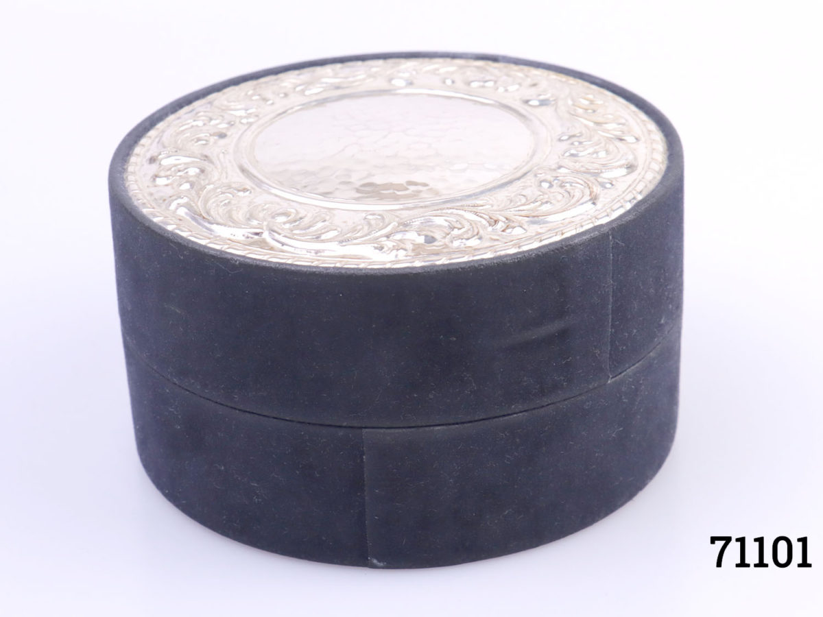 Vintage navy blue velvet covered circular box with a sterling silver disc to the top.Embossed scrollwork around the edge of the disc. Hallmarked on the outside edge of disc. Measures 115mm in diameter. Main photo of box with lid in place shown from a slightly raised eye level showing box depth