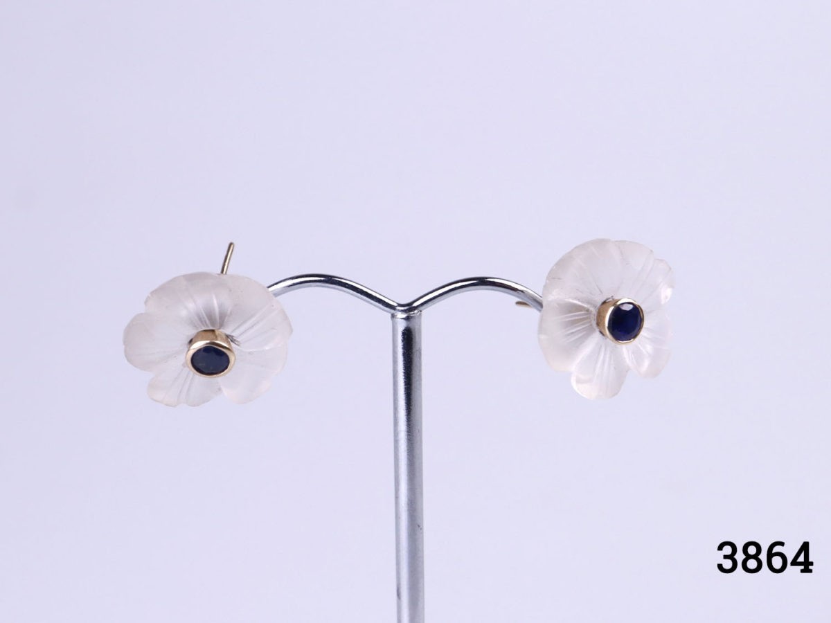18 karat gold flower stud earrings with a round cut sapphire to the centre of carved crystal flower form. The crystal flower part can be removed and the sapphire studs worn independently. Flower measures 15mm in diameter. Earrings weight 4.5 grams. Photo of earrings displayed on a stand