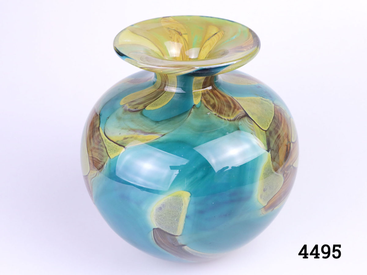 Vintage Mdina glass vase . 'Sea Swirl' pattern in turquoise blue with amber coloured swirls. Bulbous shape with turned lip. Signed Mdina to the base. Measures 40mm in diameter at base, 130mm in diameter at widest point, 82mm diameter across the top and 22mm diameter opening. Photo of vase from a slightly raised angle showing the upper lip
