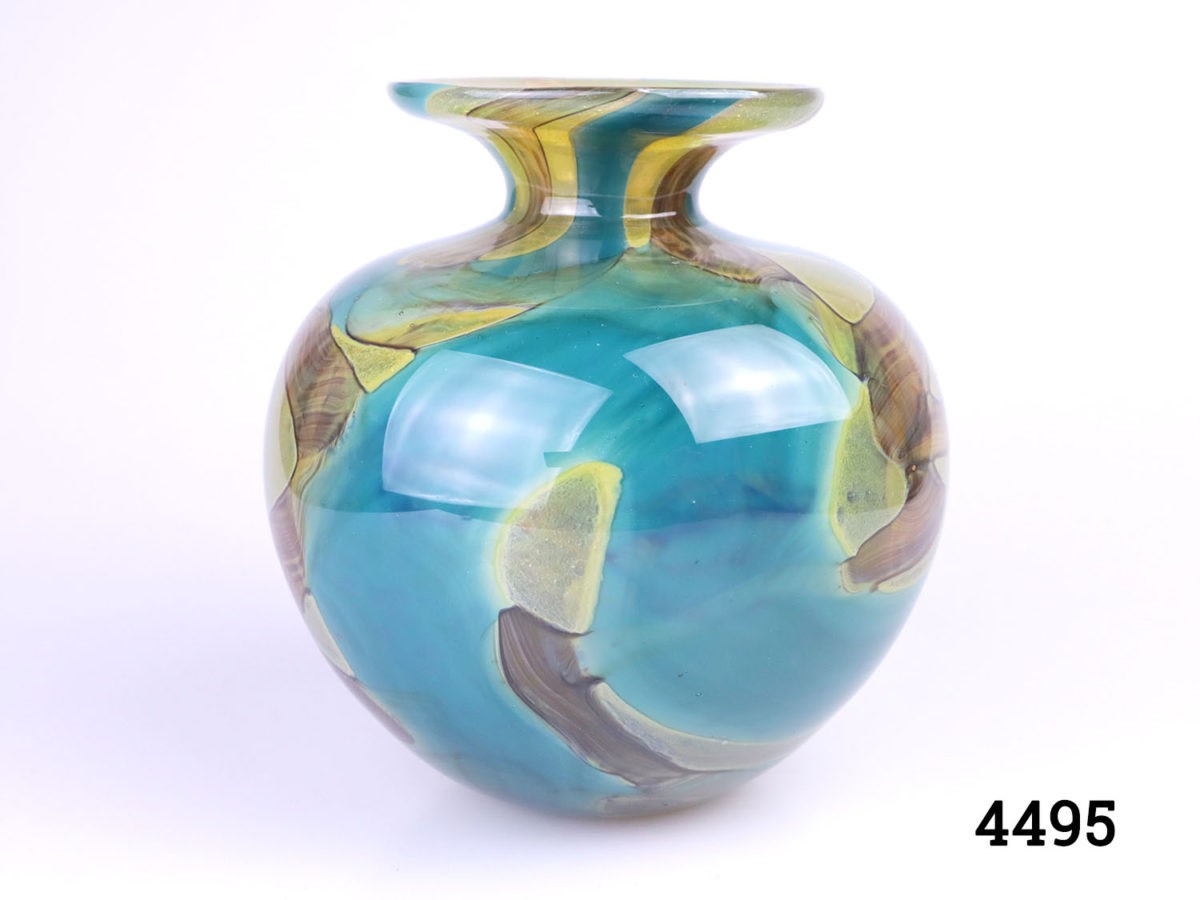 Vintage Mdina glass vase . 'Sea Swirl' pattern in turquoise blue with amber coloured swirls. Bulbous shape with turned lip. Signed Mdina to the base. Measures 40mm in diameter at base, 130mm in diameter at widest point, 82mm diameter across the top and 22mm diameter opening.. Main photo of vase seen from an eye level angle