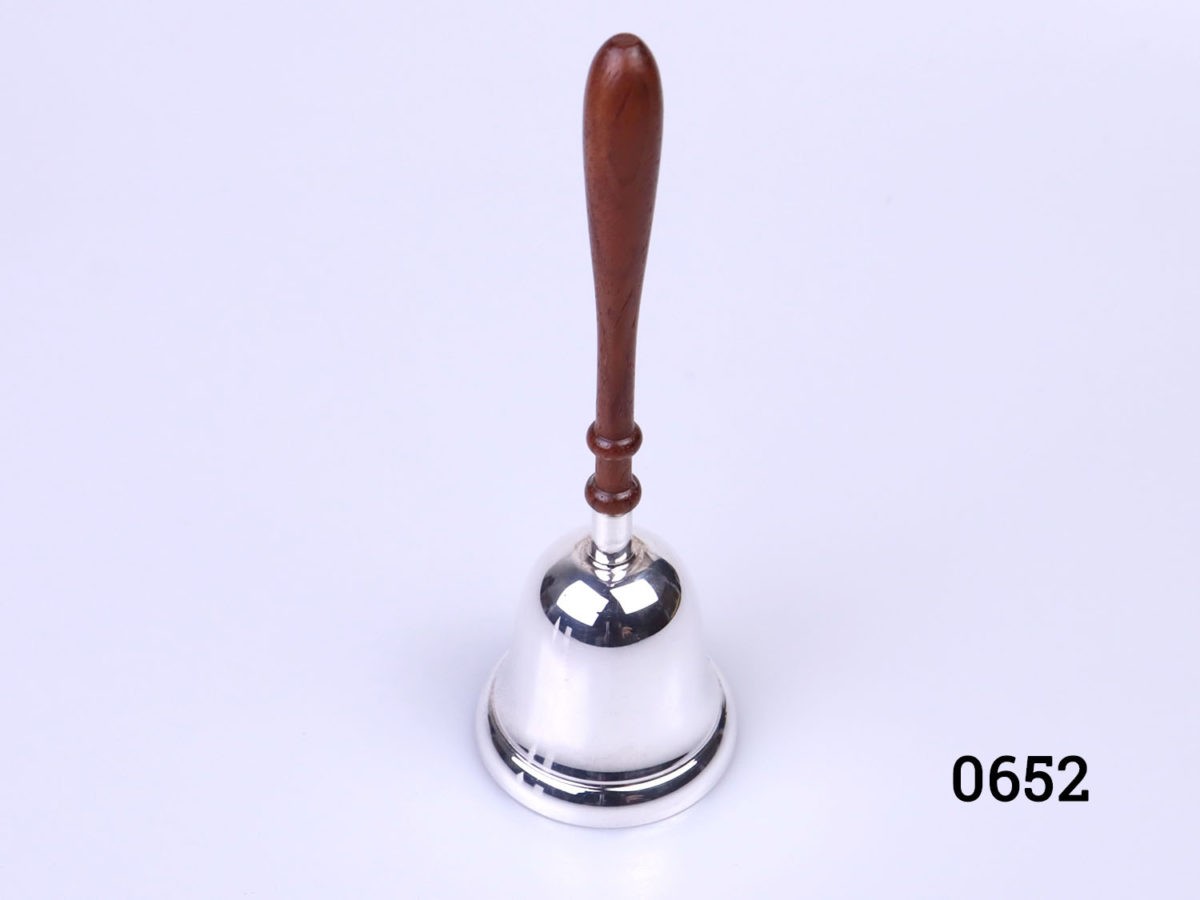 Small sterling silver hand bell with wooden handle. Fully hallmarked to the side of the bell for Birmingham assay and made by L. J. Millington c 2006. Bell measures 46mm in diameter Photo of hand bell from a slightly raised angle