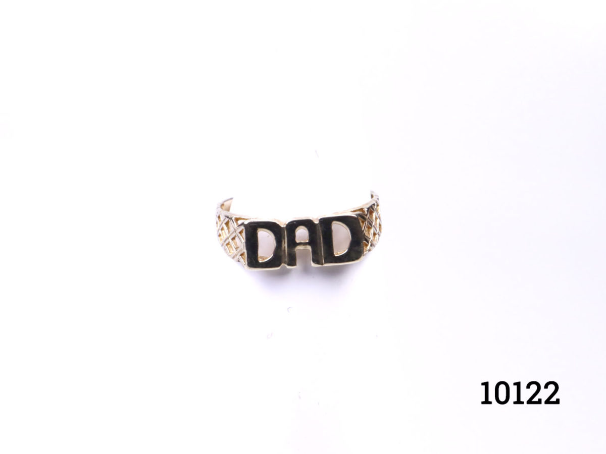 Vintage 9 karat gold "DAD" ring. Ring with Dad spelt out at front with nice lattice work to the shoulders. Hallmarked 375 for 9 karat gold. Ring size R / 8.5 and weight 1.7grams (Band is very fine at the back) Photo of ring on a display stand seen from the front