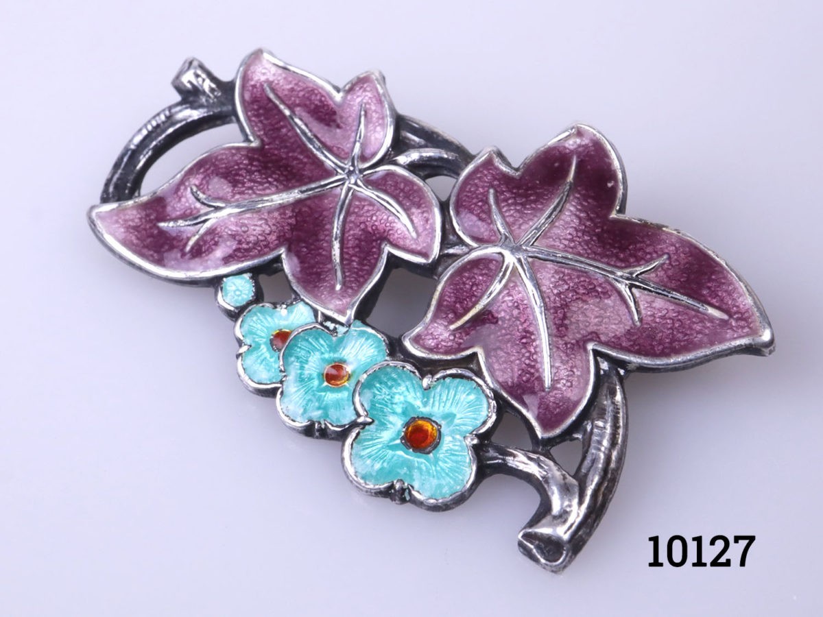 Vintage silver brooch with enamelled floral frontage. Hallmarked silver to the back. Close up photo of the brooch front