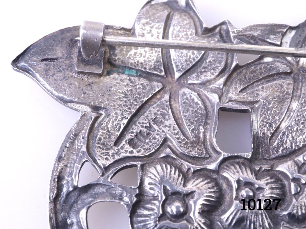Vintage silver brooch with enamelled floral frontage. Hallmarked silver to the back. Close up photo of the silver hallmark to the back of brooch