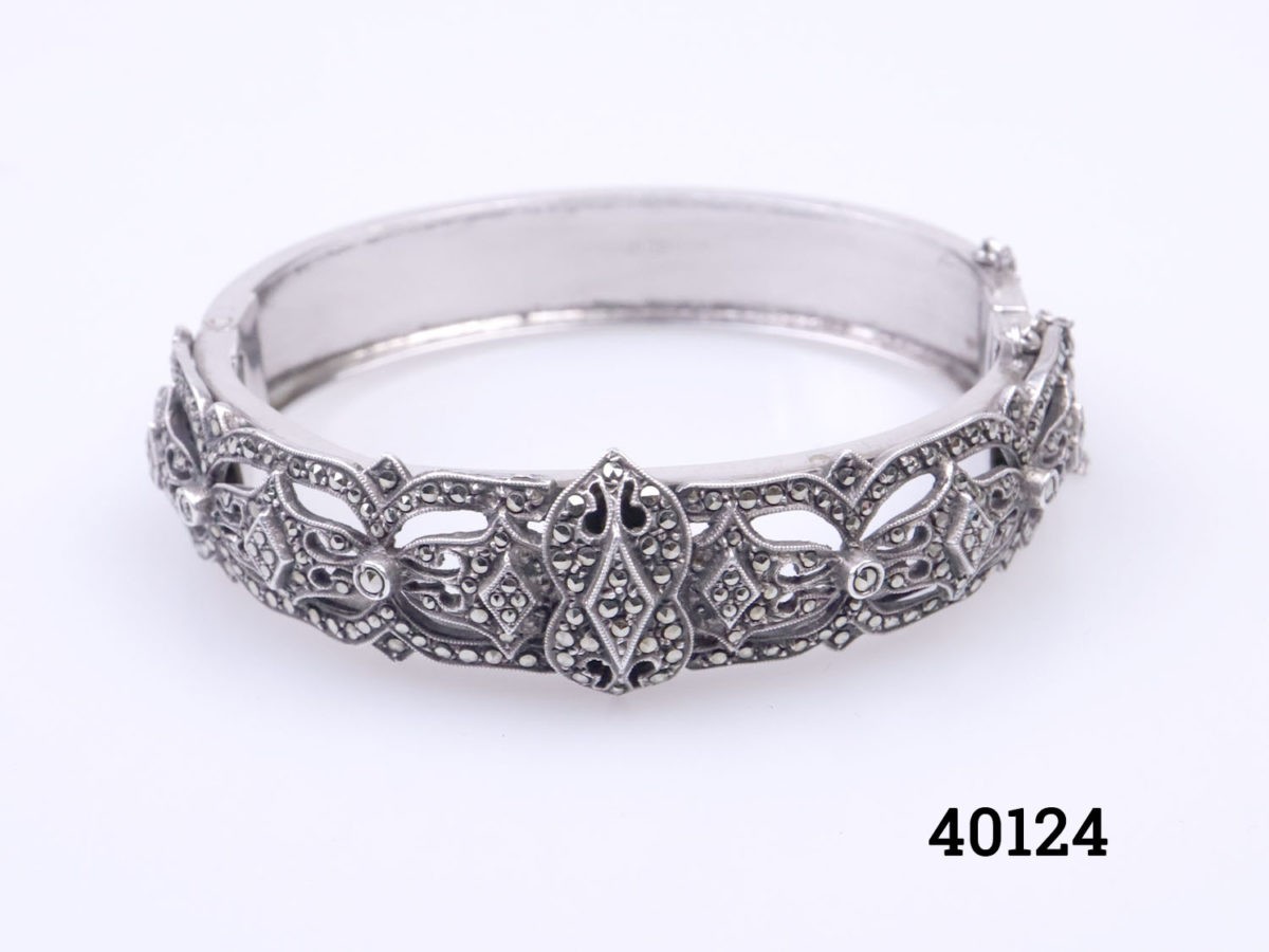 Vintage Sterling silver and marcasite bracelet. Vintage marcasite encrusted hinged bracelet with box clasp fastening and safety chain. Bracelet opening when fully open 45mm When closed 55mm by 50mm Photo of bracelet on a flat surface showing marcasite side