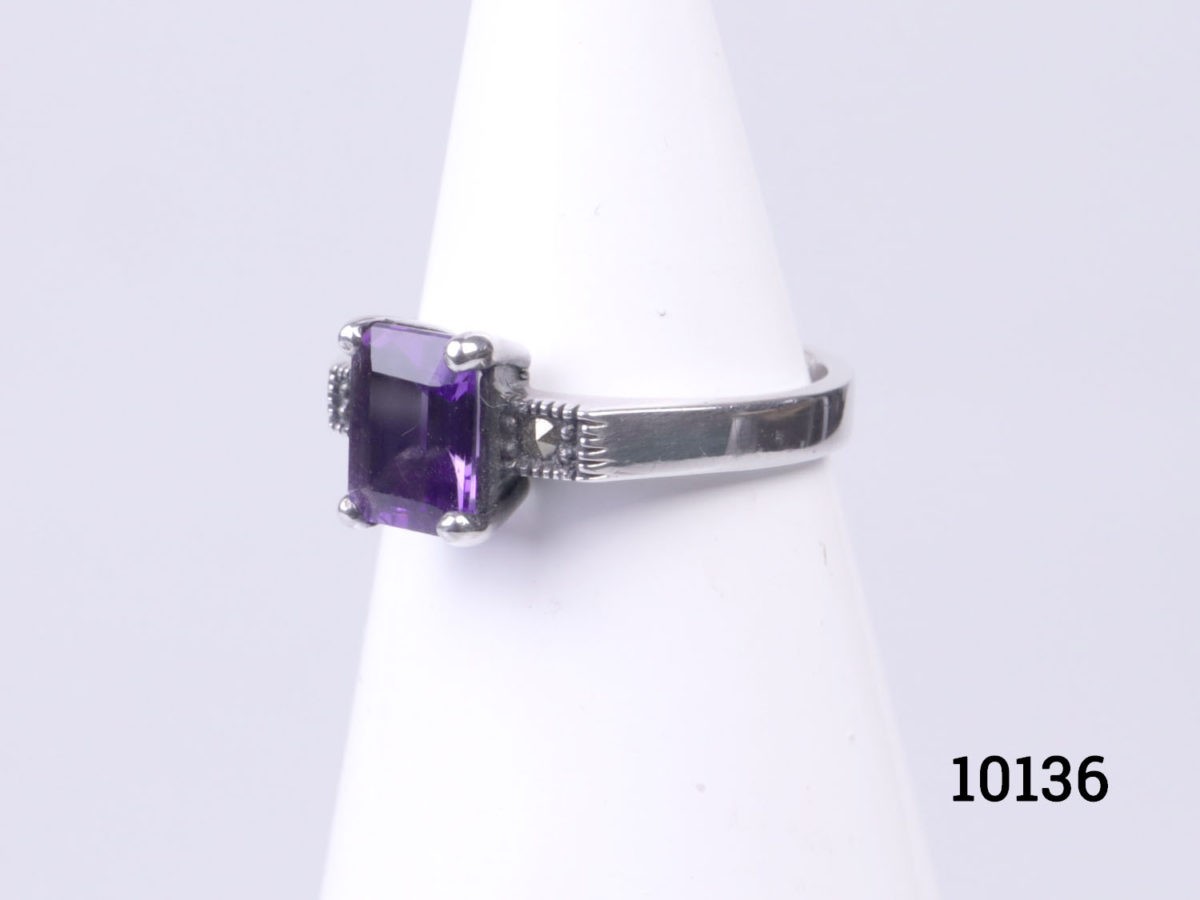 Vintage 925 sterling silver ring set with rectangle cut amethyst coloured purple crystal to the centre. Ring size P / 7.5 Photo of ring on a conical display stand seen from a slight side angle