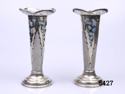 Pair of Art Deco silver plated posy vases. Small trumpet shaped vases with pale blue liner to each (One liner is misshapen at the top and missing the tip) Each measures 60mm in diameter at base and 67mm in diameter across the top. Liner measures 35mm across the top. Main photo of both vases with liners in place seen from an eye level