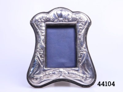 Modern Art Nouveau style sterling silver photo frame. Decorated with lily-of-the-valley flowers. Fully hallmarked to the base for London assay c1987 and made by Keyford Frames Ltd. Photograph space measures 70mm by 100mm.  Some signs of wear to the velvet. Main photo showing frame seen from front on and upright