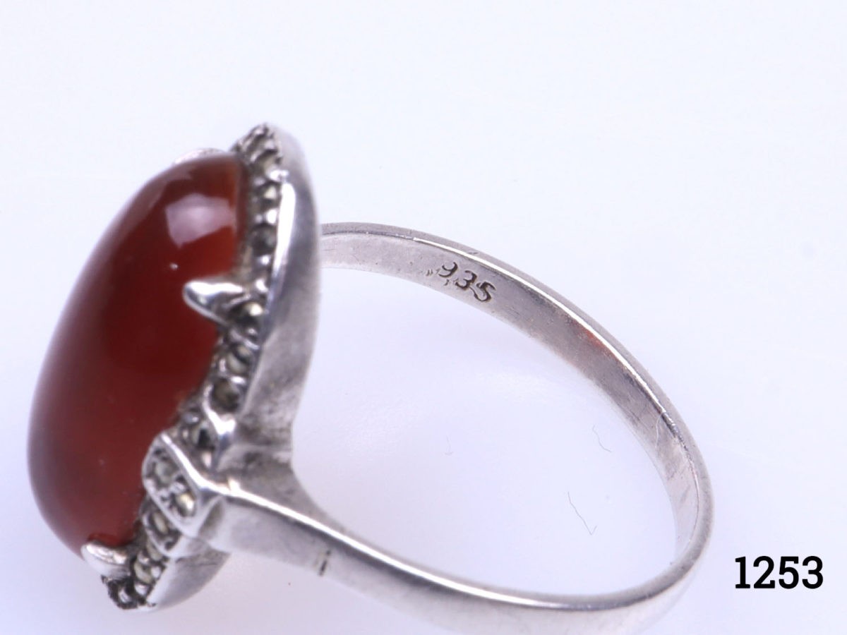 Vintage 935 silver ring set with carnelian cabochon with marcasite surround. (Some marcasite stones missing) Hallmarked 935 inside band. Ring size L.5 / 6. Ring front measures 20mm by 10mm Close up photo of the 935 hallmark on the inside band