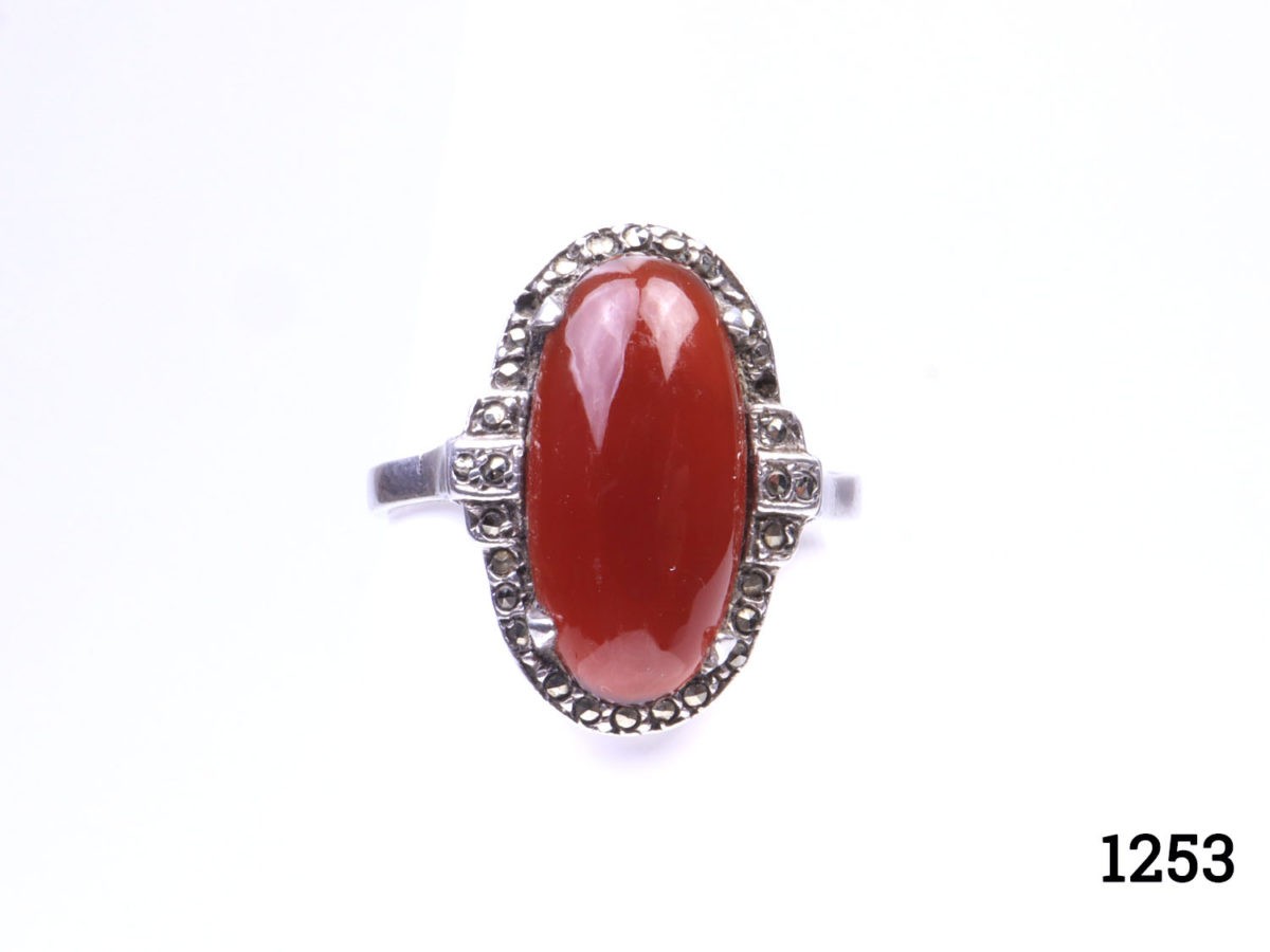 Vintage 935 silver ring set with carnelian cabochon with marcasite surround. (Some marcasite stones missing) Hallmarked 935 inside band. Ring size L.5 / 6. Ring front measures 20mm by 10mm Main photo of ring on a flat surface and seen from the front