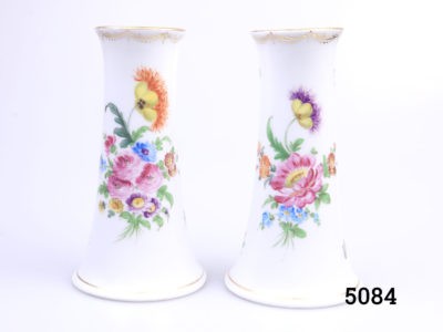Antique pair of small Dresden vases. Short chimney shaped vases with iconic floral spray design finished with gilt trim to base and lip. Some minor signs of gilt wear and a hairline crack at the base of one vase. Measures 76mm in diameter at base and 50mm across the top. Main photo of both vases side by side showing the different floral patterns to each