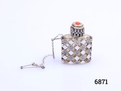 Vintage small silver perfume bottle with safety chain. Small glass perfume bottle encased in an intricate lattice work silver covering with a screw on top. Perfume applicator intact on the inner lid. Possibly a pendant previously but still could be made to be worn around the neck. No visible hallmark Main photo of perfume bottle with stopper in place and seen from a near eye level angle and safety pin to the left side