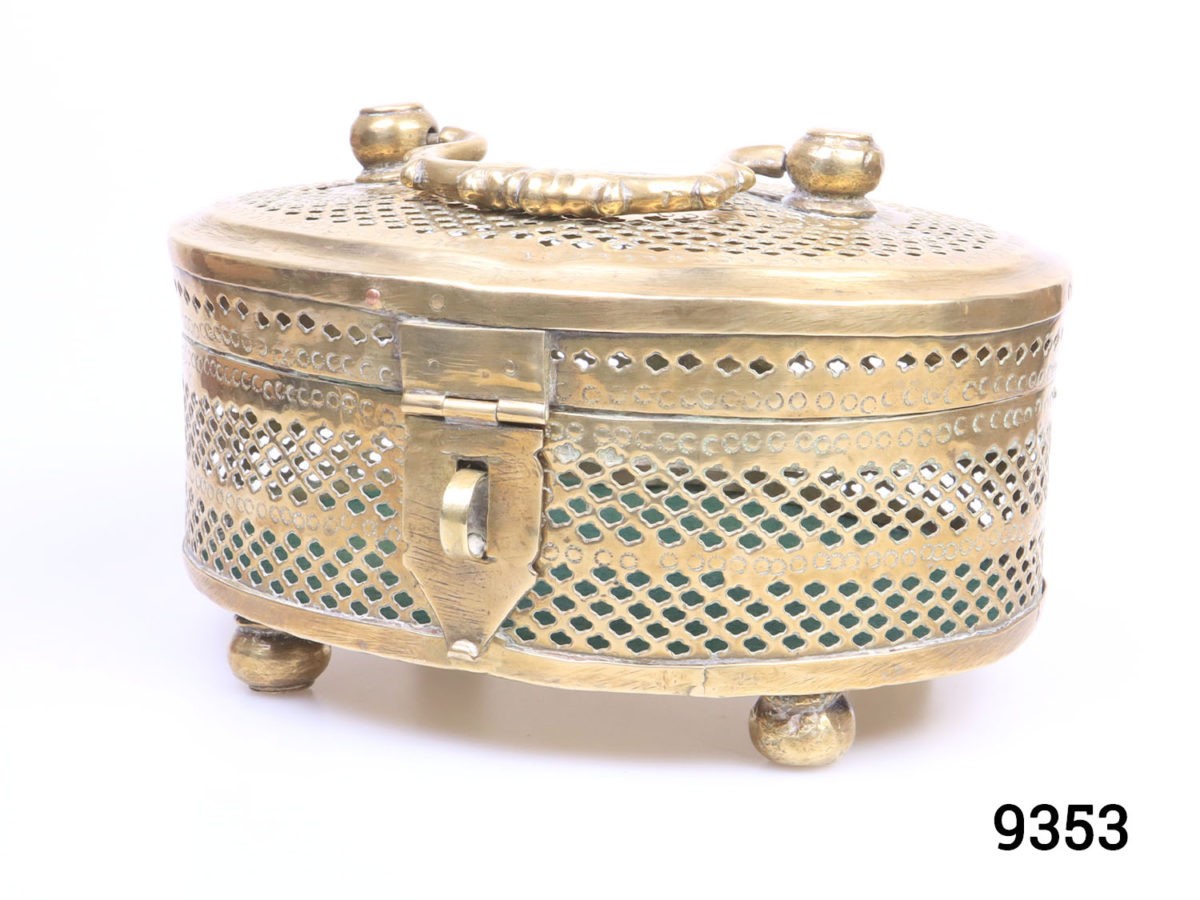 Vintage solid brass casket. Perforated solid brass casket on four round brass legs possibly used as a cricket cage or betel leaf storage case. Photo of casket seen slightly at an angle with latch facing bottom left of photo