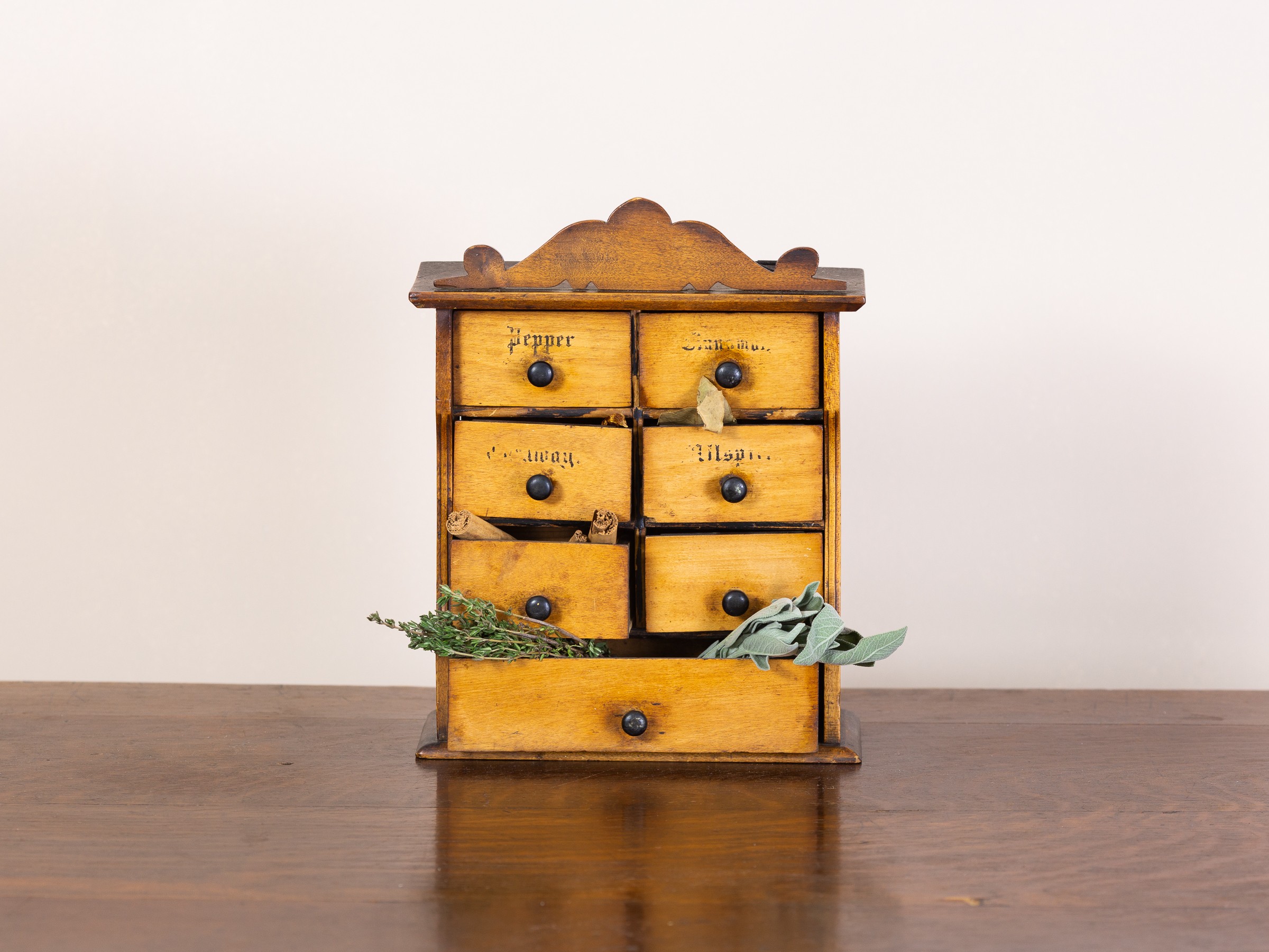 Antique small wooden spice store. Compact storage cupboard for herbs and spices with 6 small drawers and 1 long drawer at bottom. Can be used free standing or on the wall (1 hook missing)