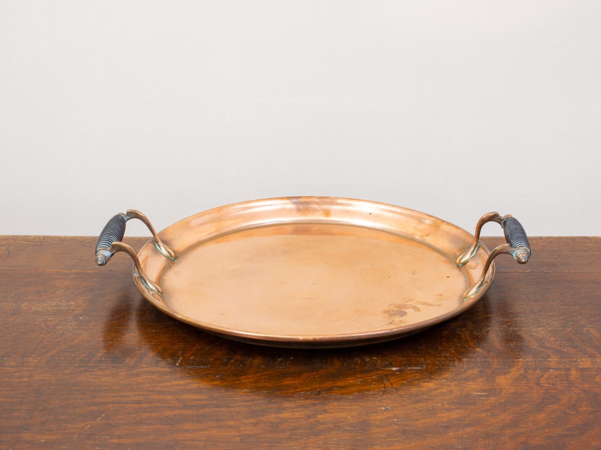 Arts & Crafts copper tray. Solid copper medium sized tray with ornate bolted handles to the side. Measures 305mm in diameter at base and 25mm deep.