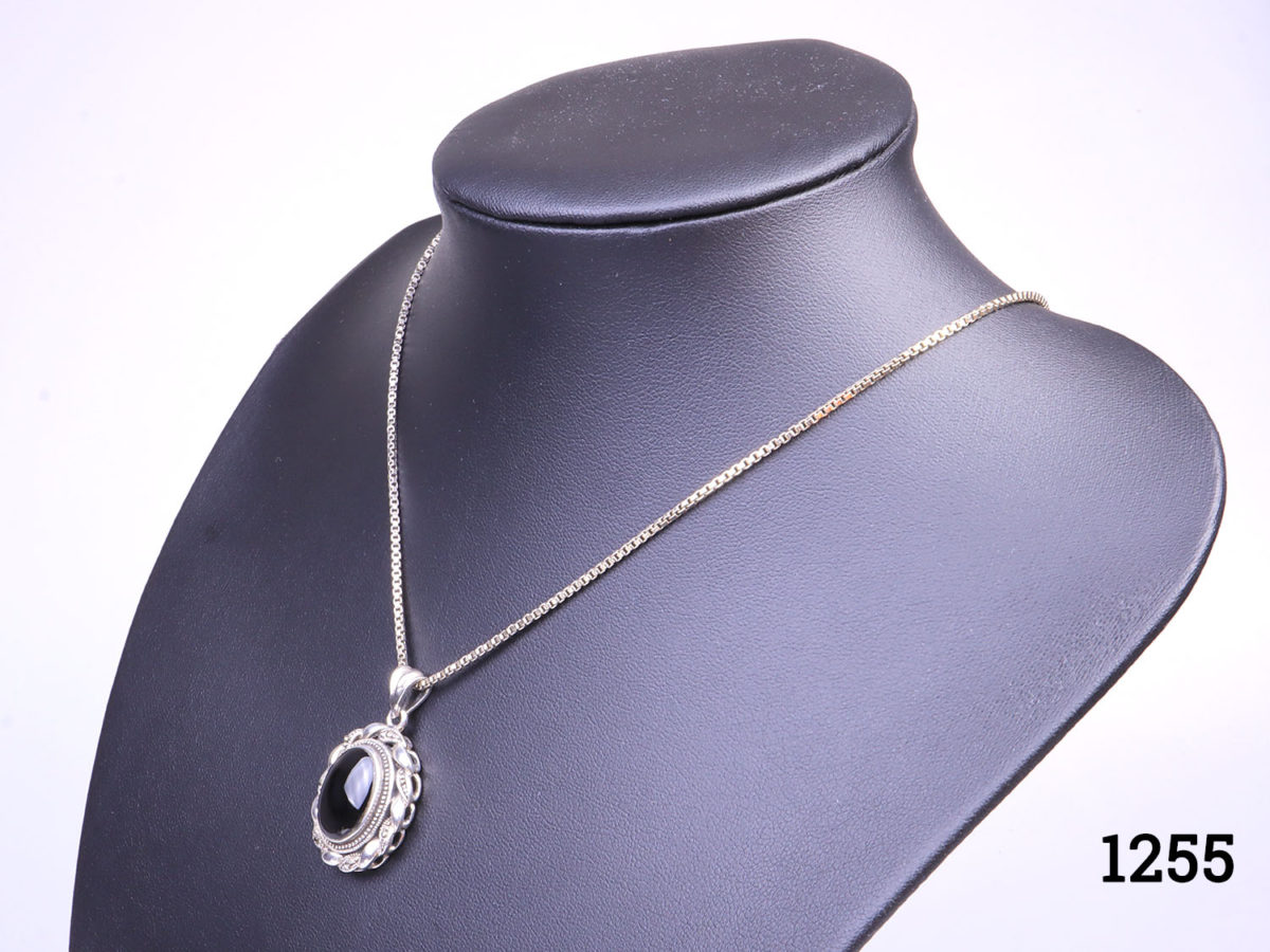 Vintage sterling silver box chain necklace with a sterling silver and black onyx pendant. Pendant drop length approximately 35mmand width 22mm Photo of necklace on a dark display stand and seen from a slight side angle