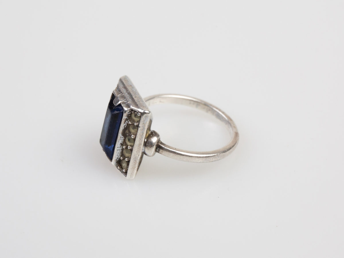 Vintage Art Deco style ring. Hallmarked 935 silver ring with a rectangular cut royal blue glass stone to the centre. Ring size M.5 / 6.5 Photo of ring on a flat surface and shown with ring front facing left