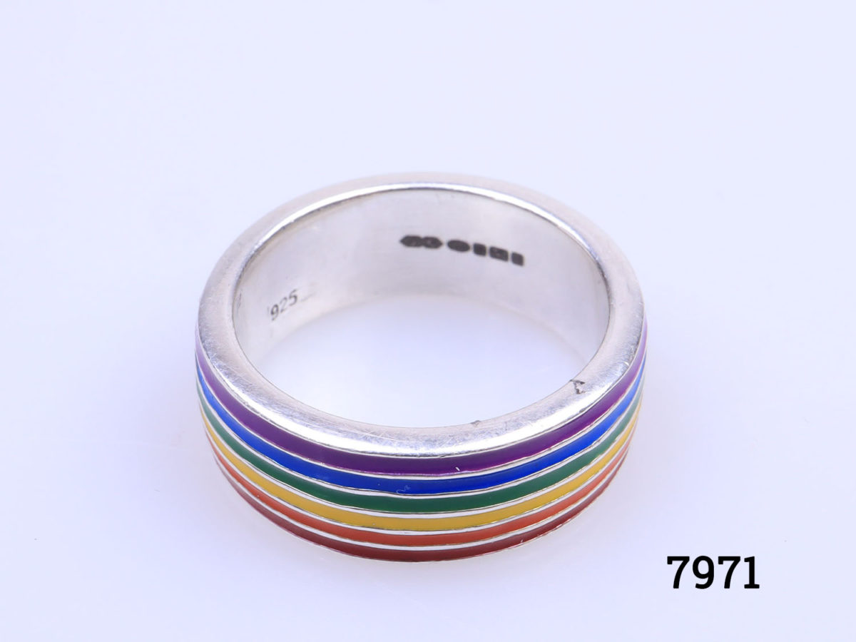 Modern sterling silver ring with enamelled stripes in the colour of the rainbow. Fully hallmarked for Sheffield assay c2019. Ring size R / 8.5. Ring Width 7mm. Photo of ring on a flat surface showing the full silver hallmark on the inside band as well as the rainbow colours of enamel