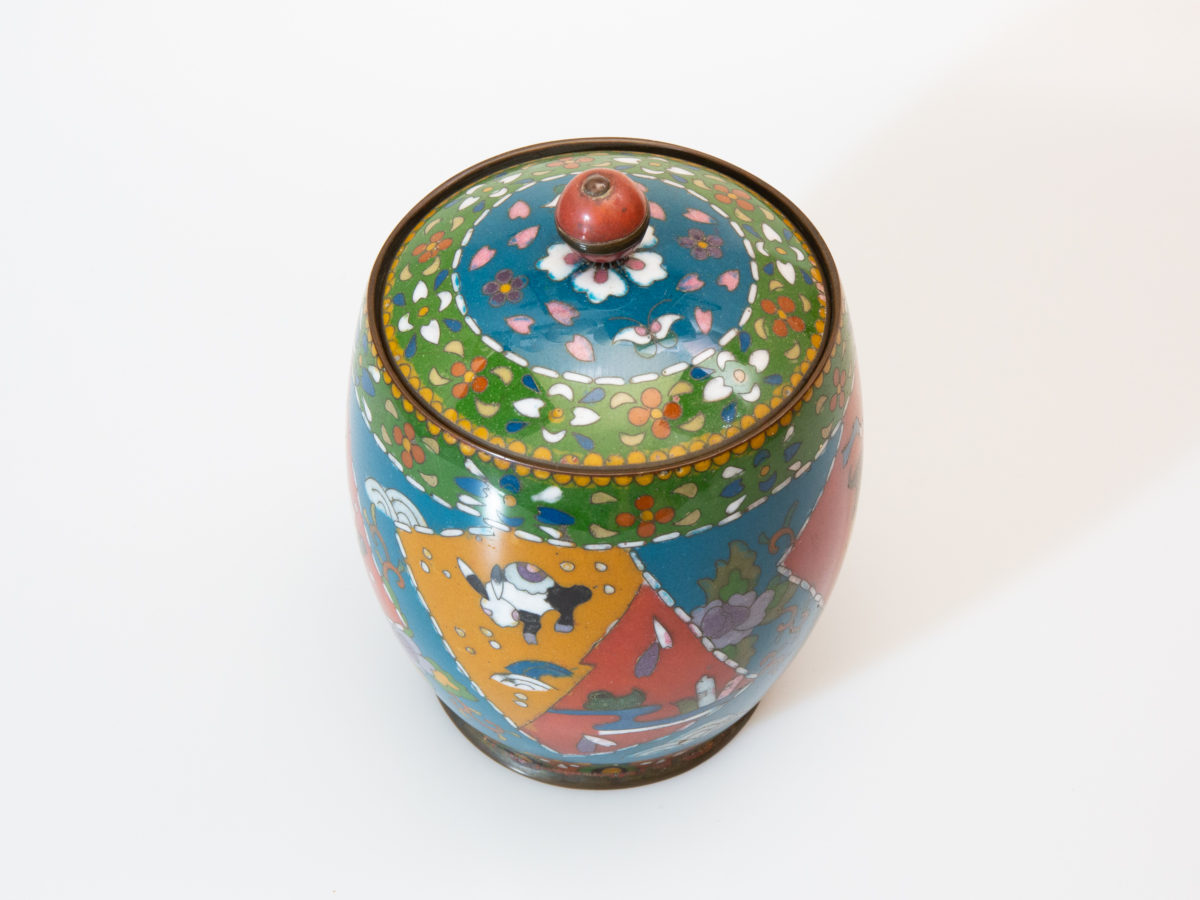 Early 20th century lidded cloisonne jar. Good sized jar in unusually muted colours for cloisonne which adds to the attractiveness of the jar. Decorated with flora and fauna to the side. Enamel in excellent condition. Finial is a little loose on the lid & needs attention. Measures 88mm in diameter at base, approximately 120mm in diameter at widest part and 165mm tall with lid. Photo of jar with lid in place shown from a slight height to show the continuation in design from edge of lid to top of jar